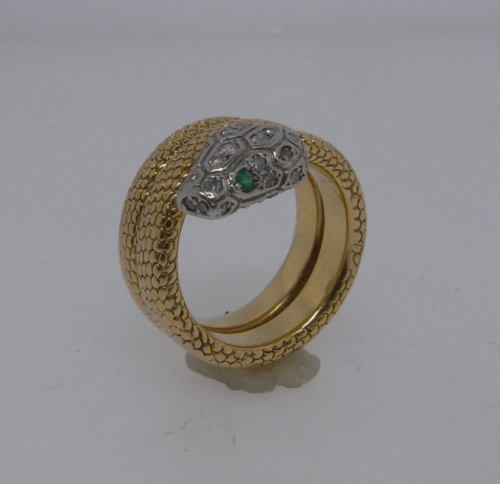 A charming ring exquisitely modelled as a snake by Cartier from the 1940's.  The gold body of the snake with textured scale detailing wraps twice around the finger, terminating in a diamond set head with emerald eyes.  Signed 'Cartier Paris' to the