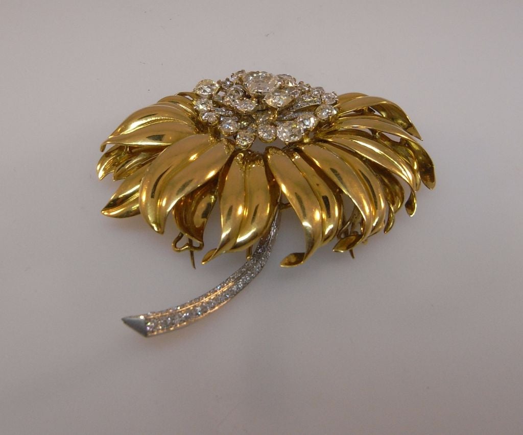 Flower clip in gold and platinum set with diamonds to the stamens and stem.  Designed as a sunflower with 16 golden petals with 25 diamonds weighing approximately 9 carats to the stamen, the stem to each stamen pave set with diamonds weighing a