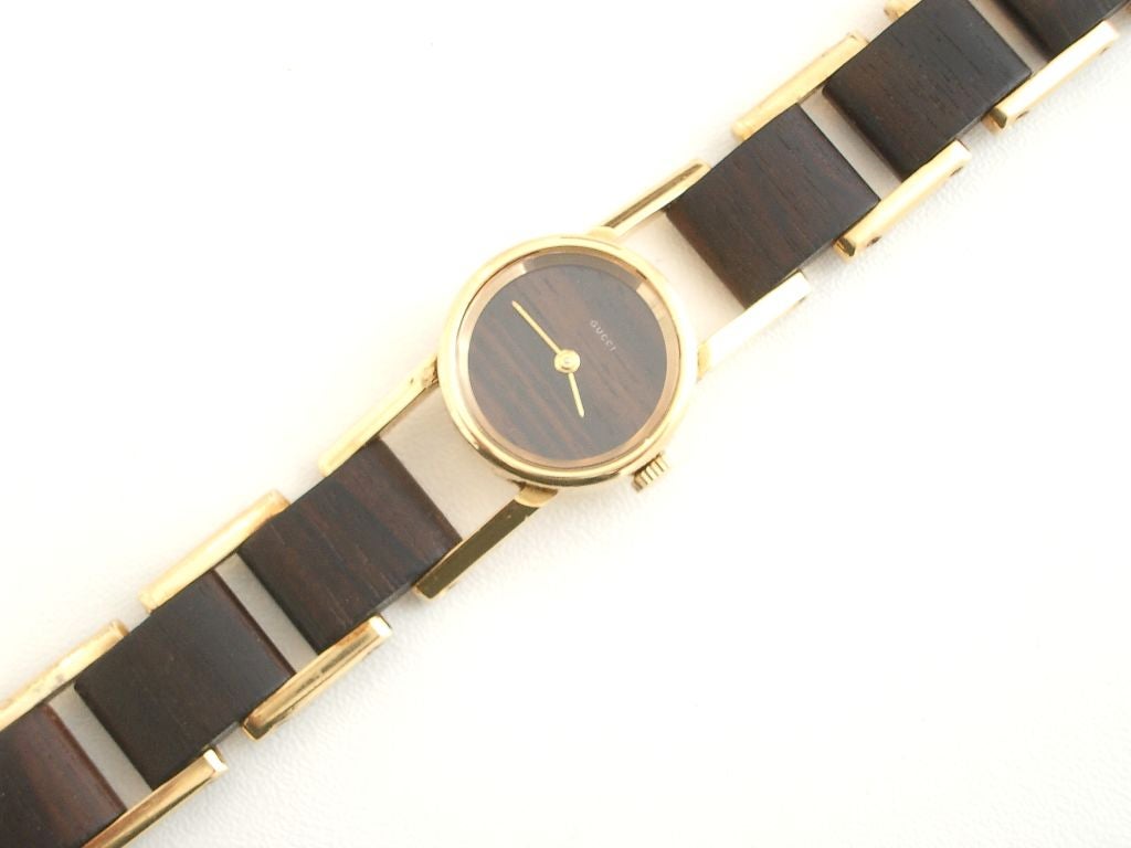 A wonderful 18k yellow gold and rosewood link watch by Gucci. The sleek design warmed by the introduction of wooden links. The face, also wood, sports the Gucci name.Marked Made in France with French touchmarks on the reverse. A great Classic piece.