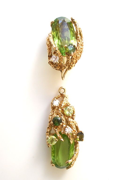 An elegant pair of Day/Night peridot and diamond earrings. The textured free formed yellow gold dangle ear clips with approximately 27cts of vivid green peridot total weight, enhanced with white round diamonds and dark green round tourmaline. The 2