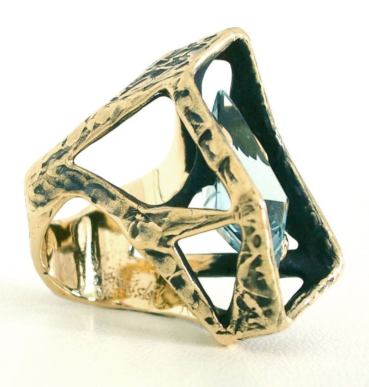 A modernist 14k yellow gold ring by Grabowski Jewelry of California. The oxidized yellow gold abstract geometric cage mounting holding a step-cut kite shaped med-blue aquamarine weighing approximately 13cts. This ring is amazing on - designed to be