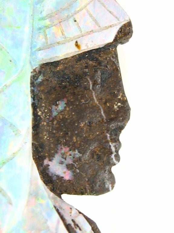 A carved opal pin, the carved profile of a moorish man, in bluish and greenish tones mounted in 14kt gold