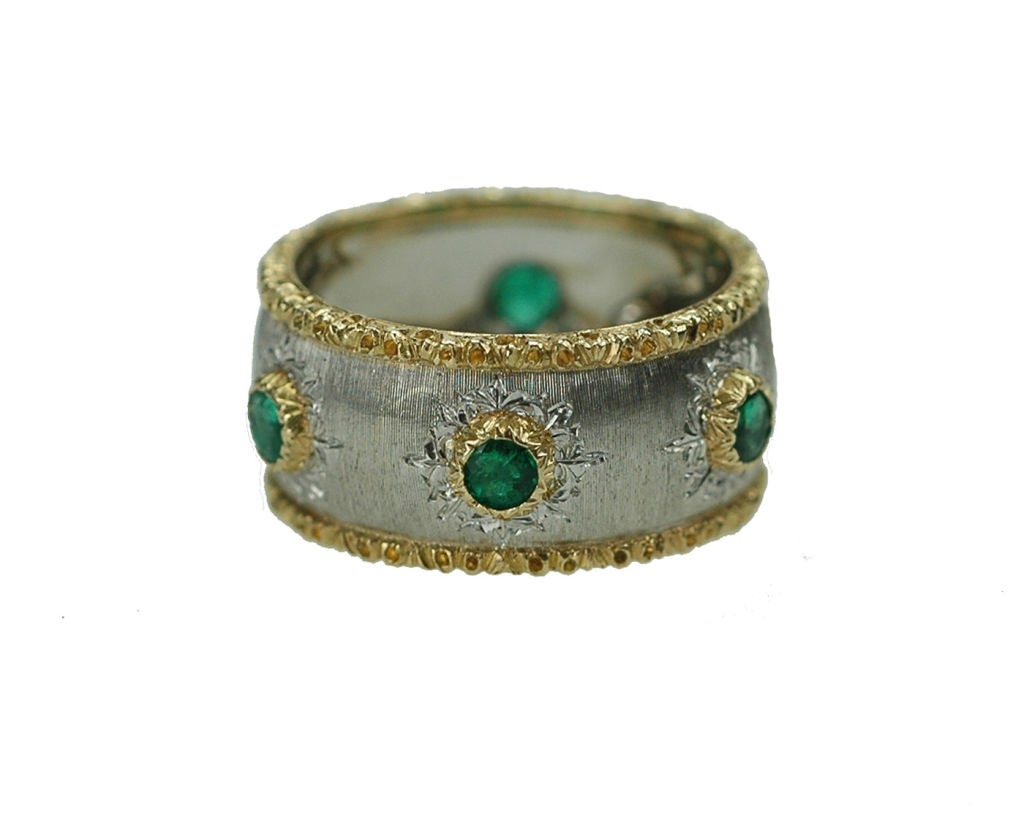Designed as a textured gold band with scalloped trim, set with 6 circular-cut emeralds in chased borders, and mounted in 18k white and yellow gold. Finger size 4 1/2, signed Buccellati.