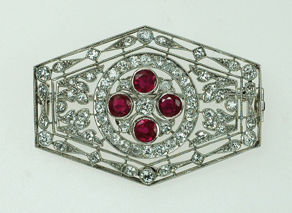 Art Deco ruby and diamond panel brooch, the hexagonal panel with a central circular-cut ruby and diamond quatrefoil cluster and an open diamond set foliate surround, with detachable frame to convert to a pendant, mounted in platinum, circa 1920,