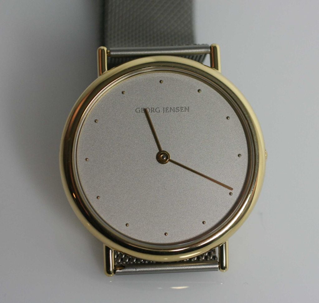 Georg Jensen watch #1347 with 18-karat gold case and stainless steel mesh band.  Designed by Claus Benderup and Torsten Thorup. This watch is no longer in production.  This watch is brand new and has never been used. Bears impressed company marks. 