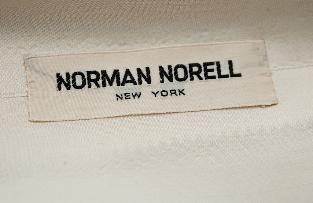 Robe de jour 2 pièces en lin moygashel ivoire Norman Norrel. Le haut sans manches est à double boutonnage avec une jupe droite légèrement froncée avec 2 poches.