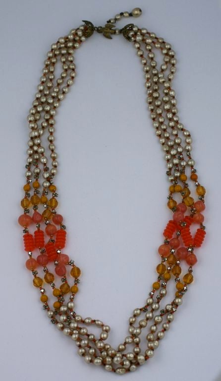Collier à 4 brins de Miriam Haskell composé de perles signature et de perles de verre en pate de verre de différentes teintes (orange/topaze/moutarde/pêche). Il y a des intercalaires en métal doré et en verre orange tout au long de la pièce et il y