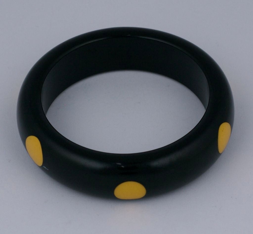 Collectible bakelite injection dot bangle from the 1930's. 6 creamy yellow dots circle the bangle in a staggered pattern.<br />
Bangle measures .75" wide.<br />
Interior width: 2.5"<br />
Excellent condition.