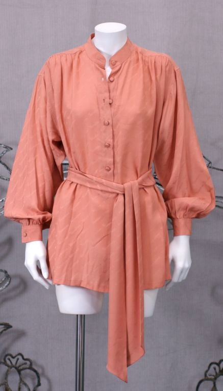 Salmon-peach Valentino silk jacquard logo tunic/blouse with self sash/tie. <br />
Poet style shirt with band collar and gathered yoke front and back. Self covered buttons on front placket with hand overcast buttonholes. 