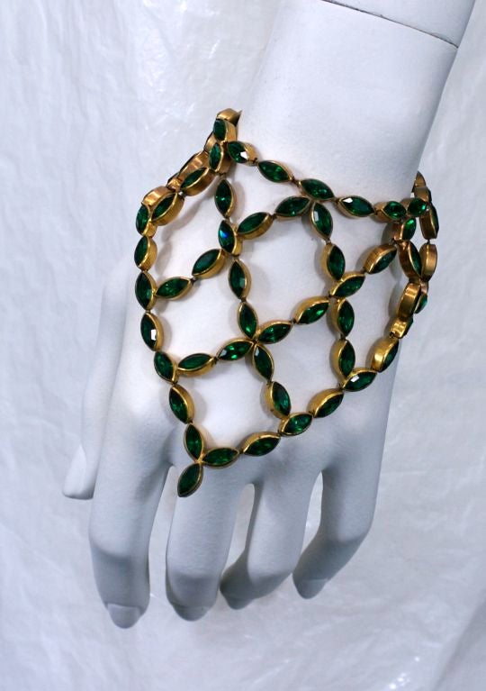 Unusual bracelets comprised of dozens of bezel set faux emeralds configured into a scarf shapes from the 1930's. Designed to drape over the wearer's hands. A flexible latticework of stones allows movement to the pieces. 

6