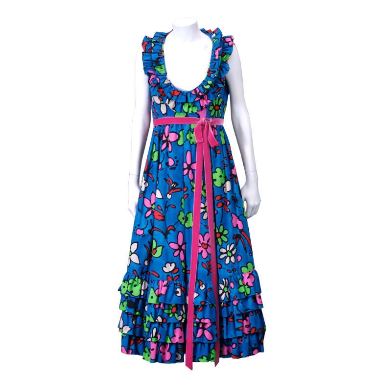 Festive party dress by Donald Brooks. Plunging neckline and hem trimmed with multiple rows of ruffles. Very full skirt falls from empire waist which is trimmed in hot pink velvet.Graphic florals in lime, red, hot pink and white. <br />
Empire