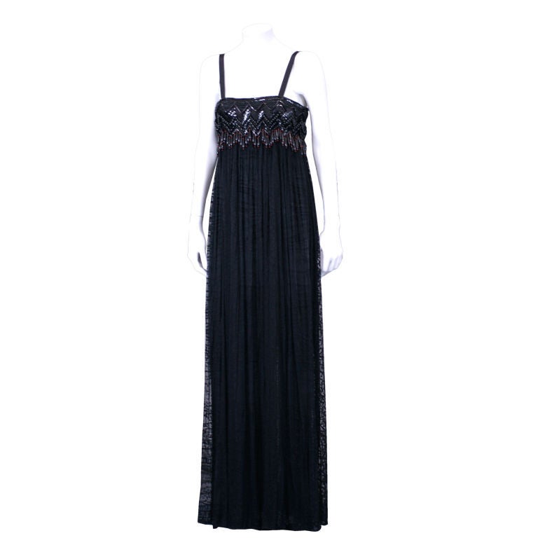 This semisheer dress is Alber Elbaz's contemporized take on Yves Saint Laurent influential African collection of  spring summer 1967.

Black sequins , ebony and deep russet dangling wood beads adorn the empire bodice.

Very full burnout chiffon