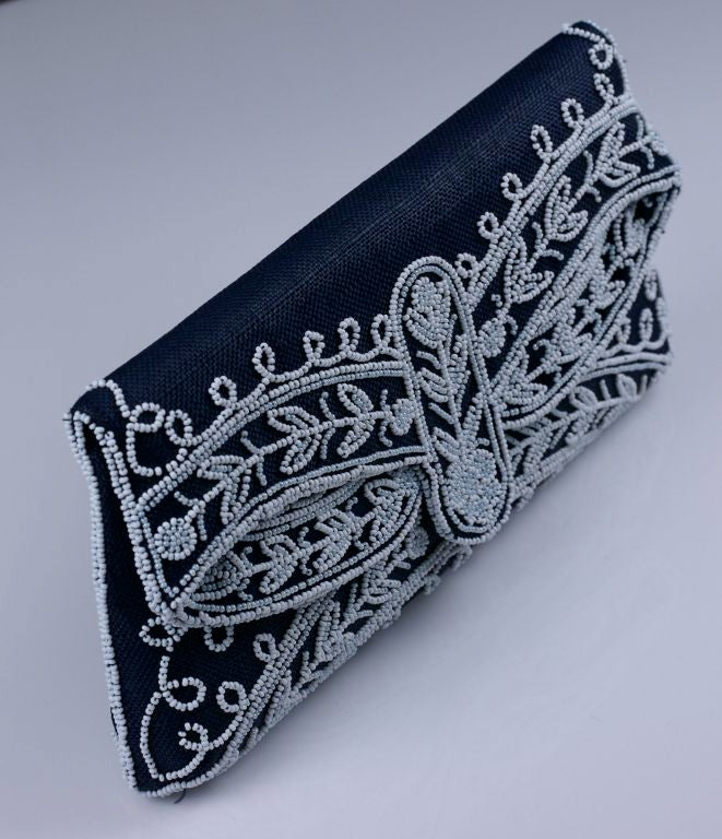 1950's navy raffia clutch with milk glass beading. Foldover and snap style  with beadwork only in front.  Satin lining.