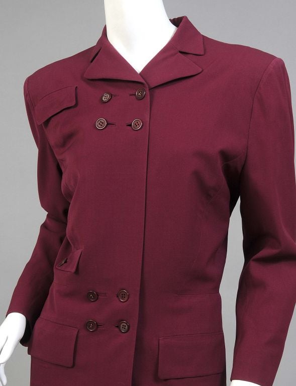 Following a successful career as a Hollywood costume designer Gilbert Adrian turned to fashion design on a much larger scale in the 1940's.<br />
<br />
This claret colored wool suit is a striking example of his exquisite tailoring.  The trim
