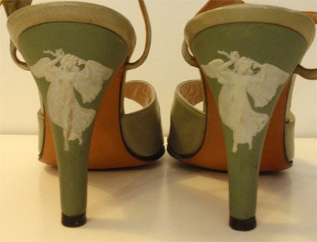 This is a pair of lite green vintage heels by Ravne, from the 1950's. They have a porceline heel with a white detailed angel with wings, an adjustable ankle strap and open toe. The heels are a size 6, with a 3.5