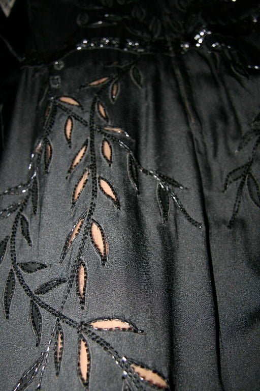Early 1940s Black silk crepe beaded cocktail dress w/dolman sleeves. Long black beaded stitched length ways around V neck, hips and arms and hem, with slits. Beads around leaf design with mesh and stitching. The mesh shows through to the skin. Zip