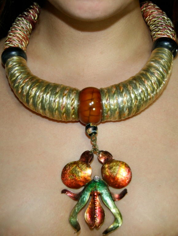 Ethnic-inspired, bulky necklace, made out of rope, silk ribbon, burgundy, pink and shades of green at the back with metal hook closure. Wooden (ivory?) beads and then metallic ribbon with braided silk covered in a metallic, gold plastic (?) coming
