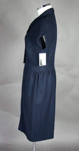 Navy Blue Wool Late '50s Dress. Two buttons in the front with pleated skirt. Two side pockets. Dolman sleeves. Silk lined.<br />
<br />
Measurements:-<br />
<br />
Bust - 42