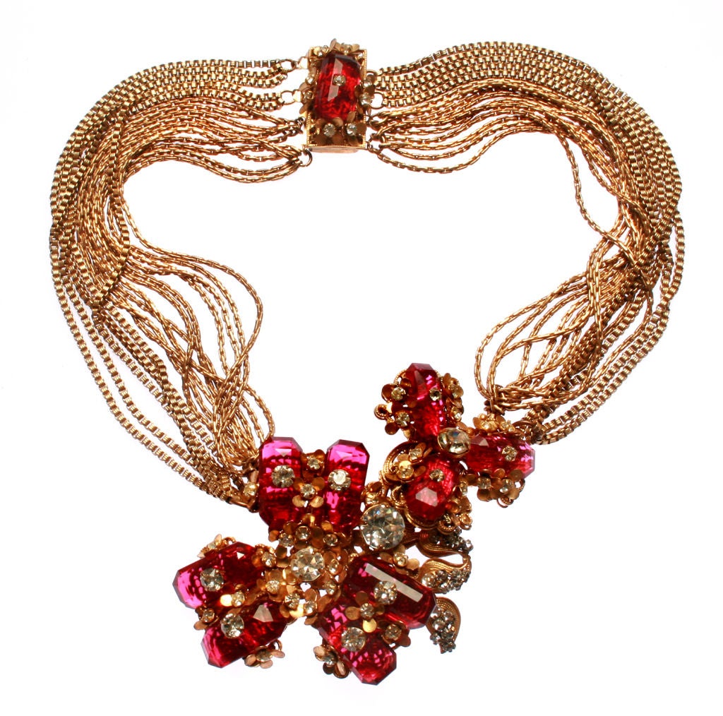 This is a beautiful multi strand Haskell necklace with ruby colored faceted glass flowers with rhinestone accents.
It is 14” long.
Center piece measuring 3.”w x 2.”h