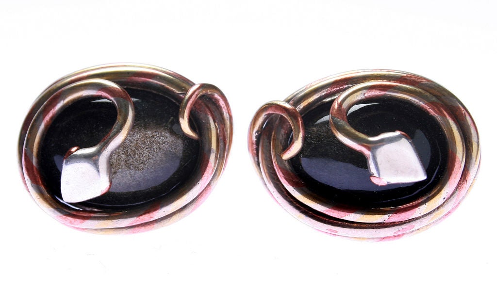 These are wonderful cufflinks.  The shanks, base and snake head of the cufflinks are sterling; the pattern of the snake body are a combination of copper, brass and silver which encircles a black stone with a golden sheen. The marriage of mixed