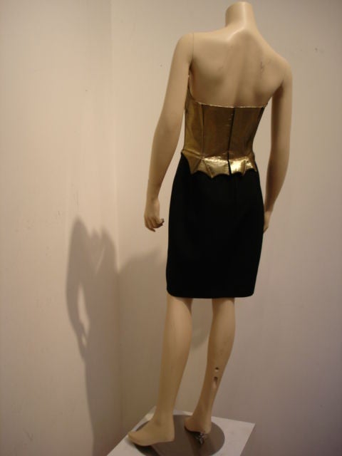 Severely tailored 3 piece ensemble consists of boned flamed gold lamé bustier, fitted tuxedo jacket with sculpted flame collar and black fitted skirt.