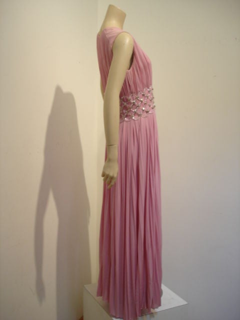 Silk jersey liquid pink gown with knife pleats and dramatic Lucite ring details around waist.