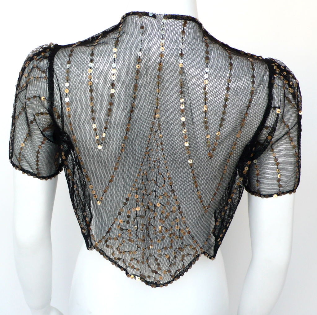 This 1920's french lace caplet has capped sleves and bronze sequins sewn throughout creating a beautiful deco design. It has been kept in pristine condition.