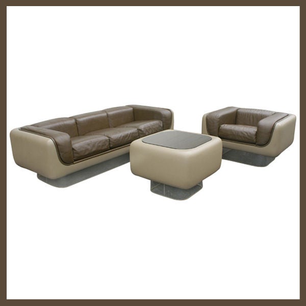 Three piece grouping of Soft Seating designed by Warren Platner for Steelcase. The group consists of a three seat sofa, lounge chair, and end table.  Clear acrylic bases under tan fiberglass bodies with brown leather trim and detachable cushions.