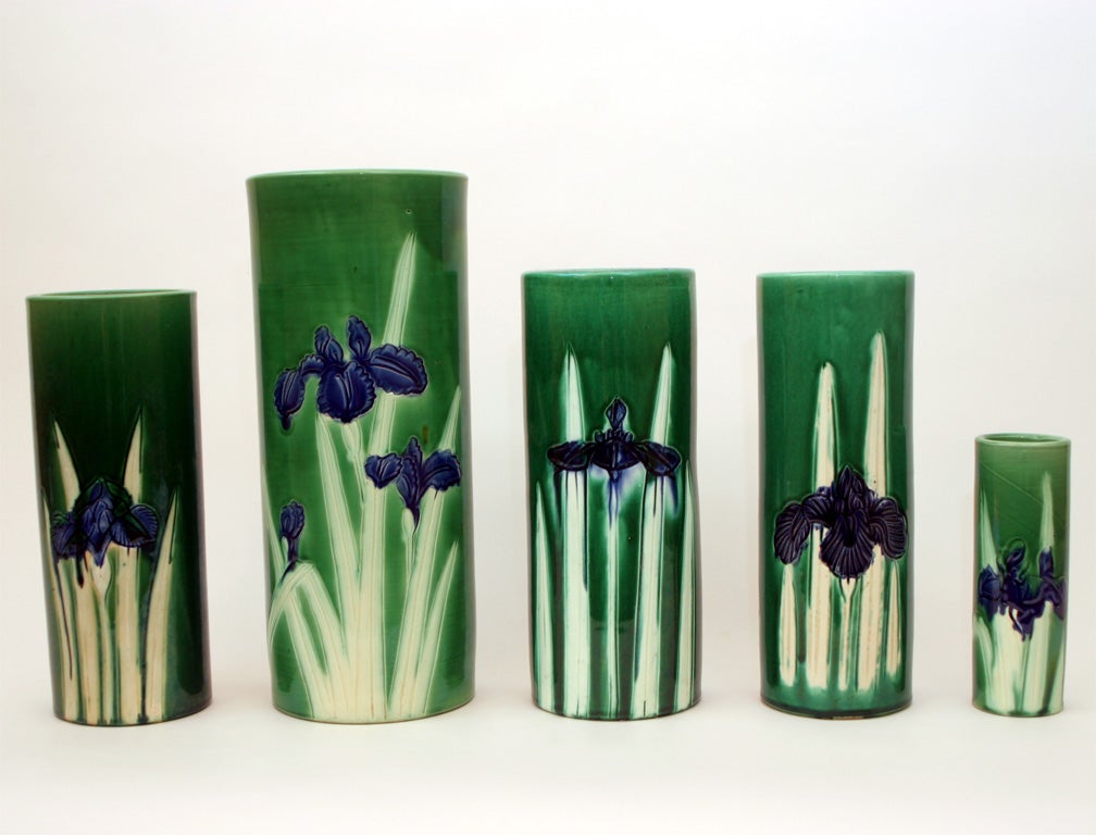 Nice grouping of cylindrical vases of varying size with incised blue irises on deep green ground.  Hand thrown. Circa 1910 - 1930. Two with professionally sealed hairlines.