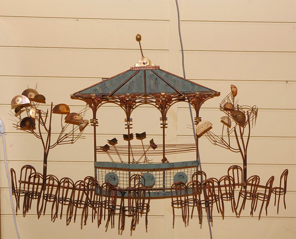 Beautifully detailed metal sculpture of an outdoor gazebo, happy little trees and a grouping of chairs for the audience.  The mixture of the gold, bronze, and patina finishes makes this piece stunning.