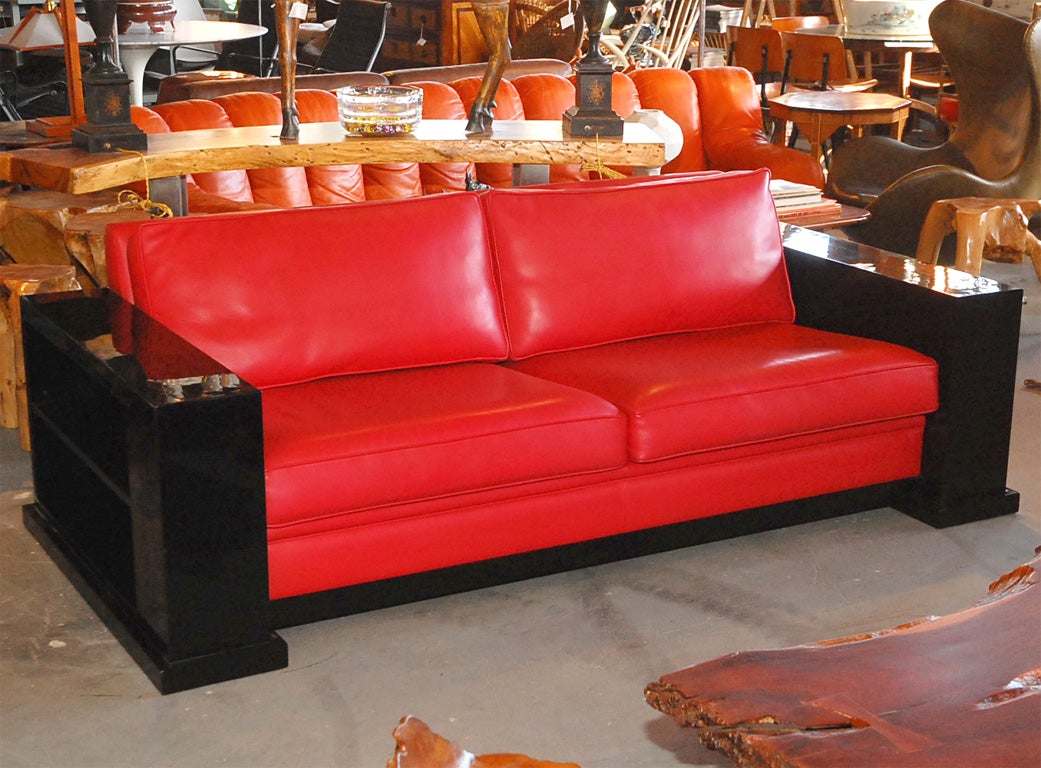 red leather and black lacquered sofa with shelving built into sides of arm-rests