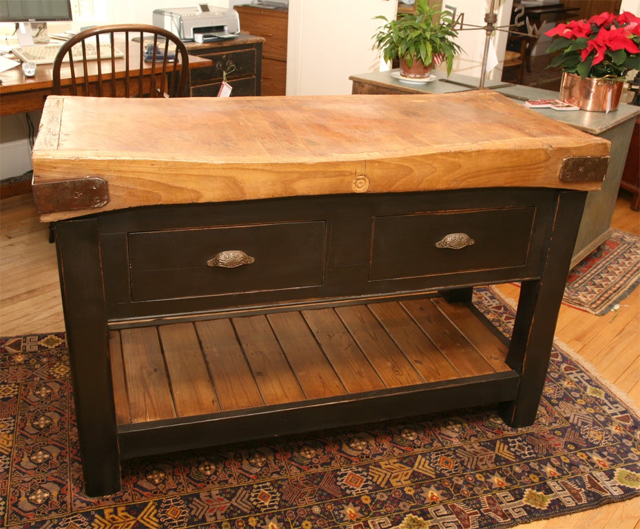 The hard maple top of this original butcher block has been happily married to a striking antiqued black base. the base has two large deep drawers, with brass pulls, that can be accessed from either side because they pull out from either side. Below