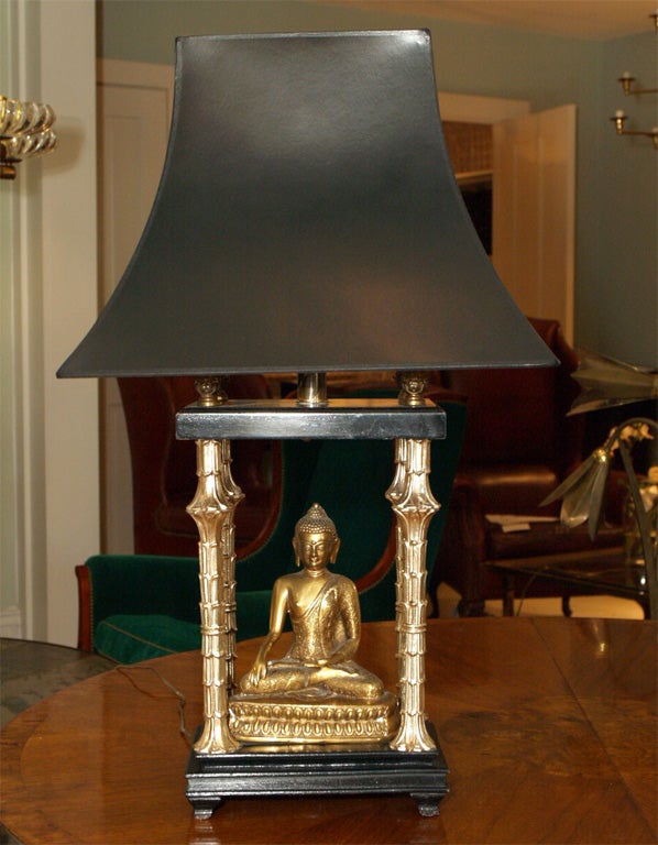 Diminuative table lamp with cast brass buddha among four stylized lotus stalks in plated metal; ebonized stepped plinth and canopy; shade available but not included in price; measurement to top of socket