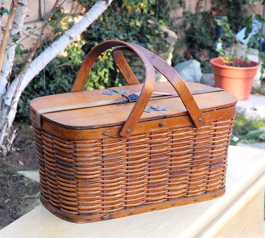 C. 1930-40 woven wood picnic basket. This basket is made by Hawkeye and has a quarter of the inside metal liner divided up for a refrigerator. They would put ice and salt in that section and keep items frozen back then. It has wood handles, and the
