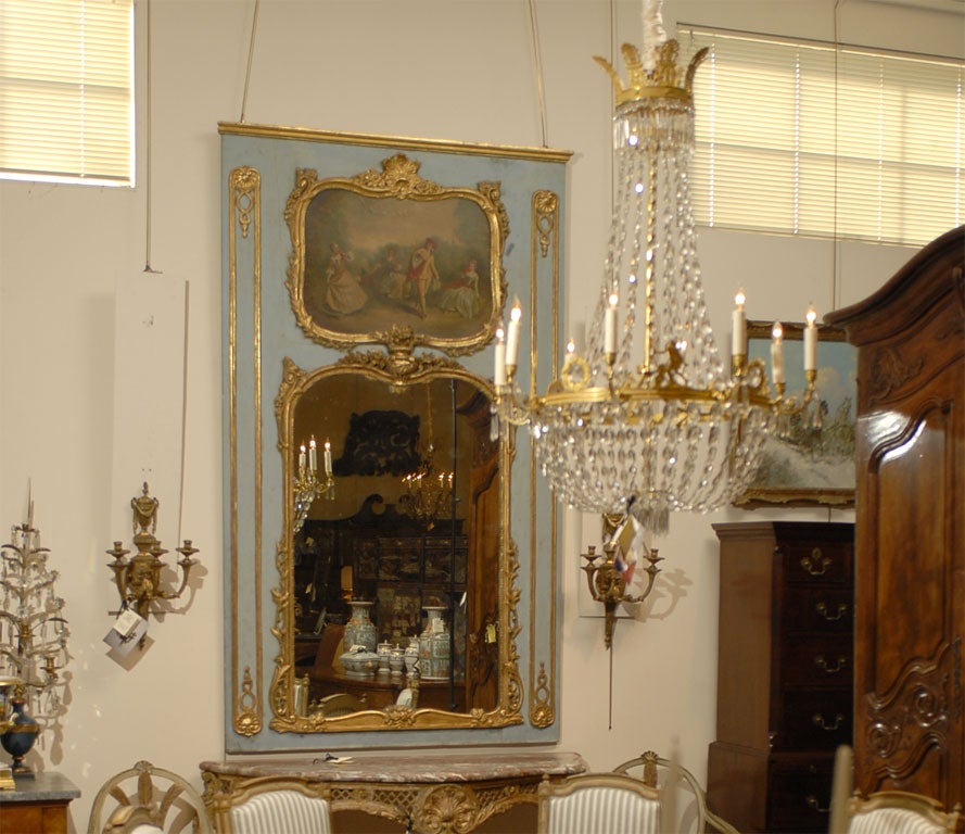 A fine and very large Trumeau mirror, dating from the Louis XV period, and French in Origin. The frame with carved designs in the Rococo taste, and decorated with gilt accents on a blue-painted ground. 

The mirror's upper section featuring a