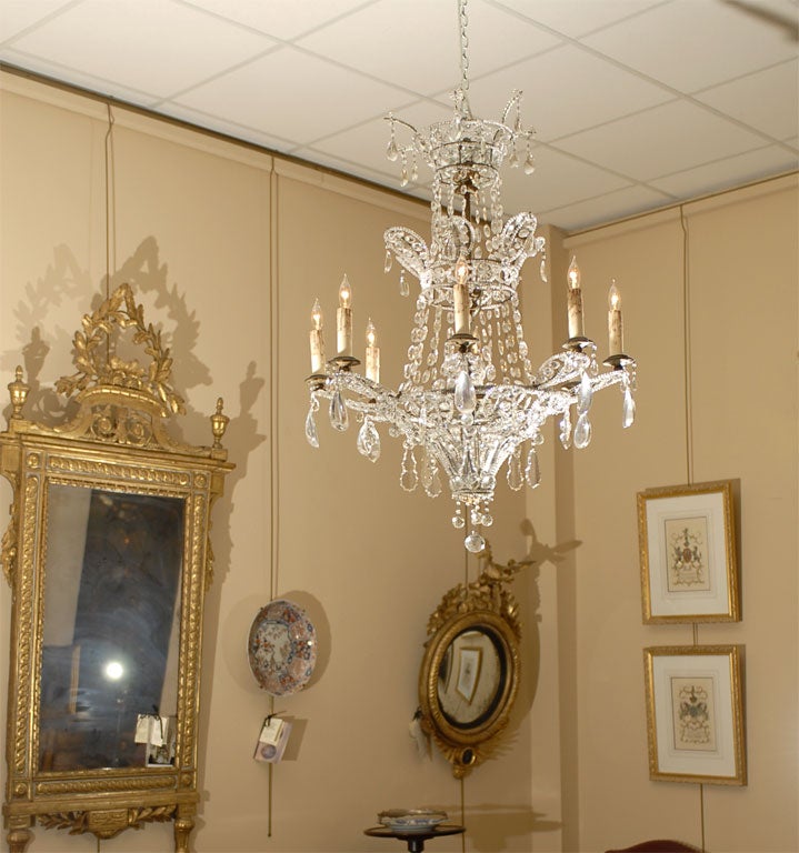 A neoclassical-design cut-crystal chandelier with 8-lights, originating in the Baltic region, and dating from the late 1800s.

The eight candle-arms arranged on a single tier, with 'palm branch' crystal groupings extending below each arm. 

The