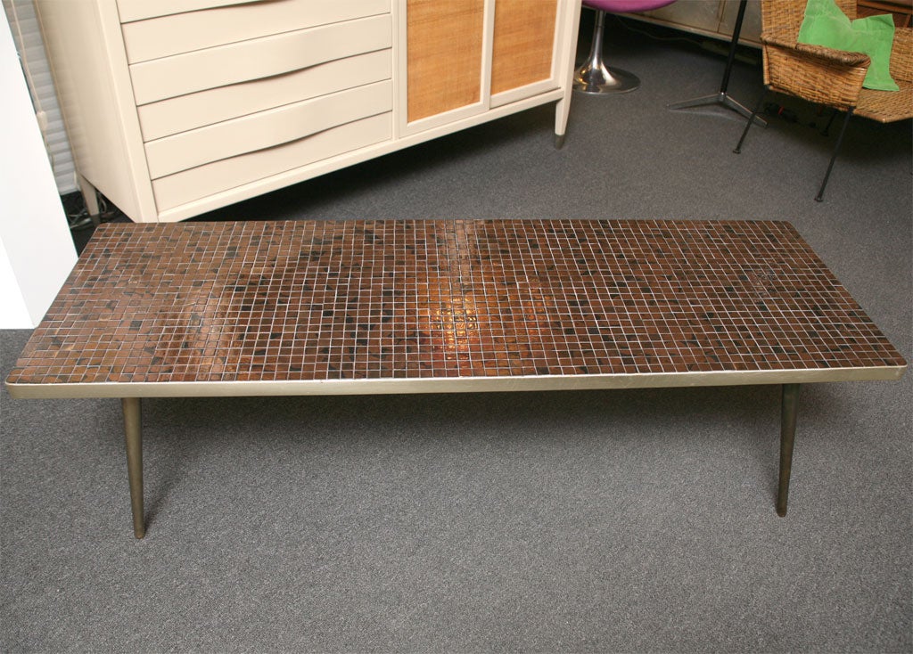 Rich metallic Gold & Bronze glazed tiles adorn the top of this 50's Coffee Table with bronze patinated tapered legs.  Rectangular with a gold anodized aluminum skirt edge.  Excellent vintage condition.  Beautiful tessarae tiles laid down on solid
