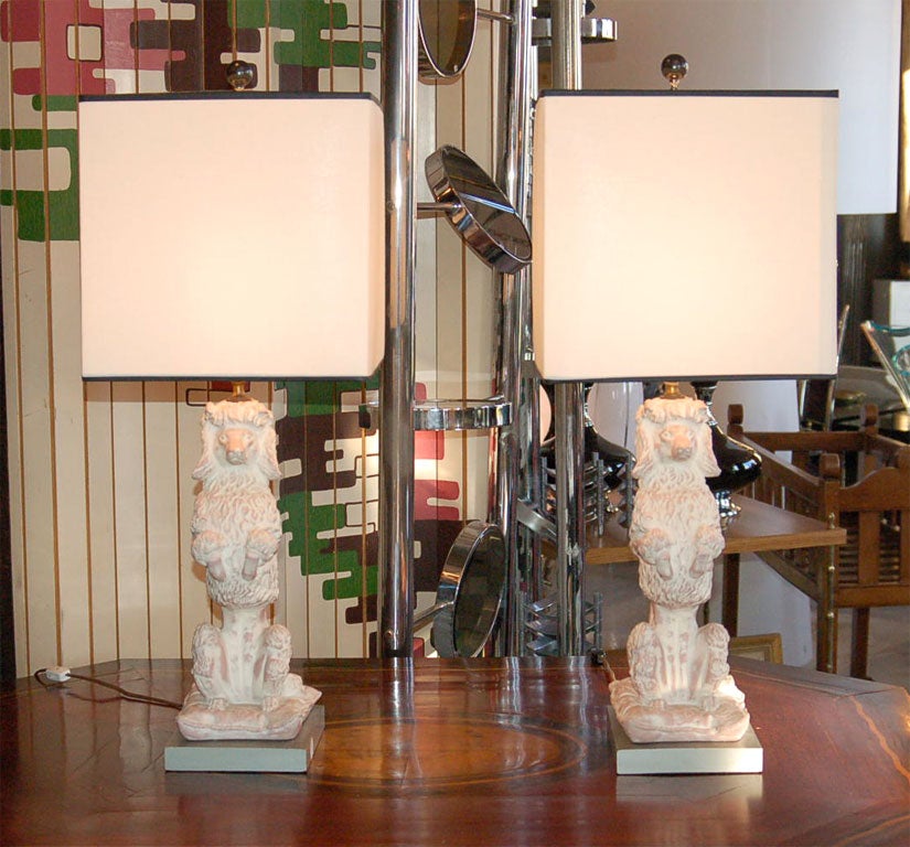 Fabulous pale pink poodles make a wonderful pair of lamps. They seem to be a custom pale (limed terra cotta) pink paint job over heavy plaster of paris. Lamps are complimented by the shades which are 
