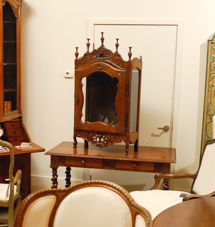 A petite French Louis XV period walnut vitrine display cabinet from the 18th century, with single glass door and richly carved floral-themed motifs. Created in France during the 18th century, this small Louis XV walnut vitrine features a scrolling