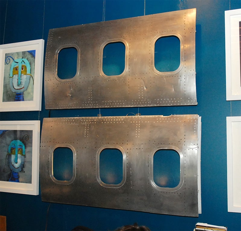 These wall lights are constructed from sets of airplane windows. The paint has been stripped so the finish is brushed aluminum. Lights have been added discreetly behind each window opening, creating a lovely glow. At their deepest point these lights