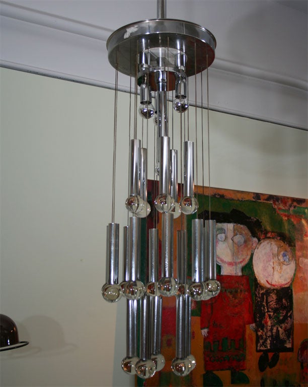 Twenty chrome tubes topped with glass balls dangle from the circular base by chains. Four lights illuminate this unique chandelier.