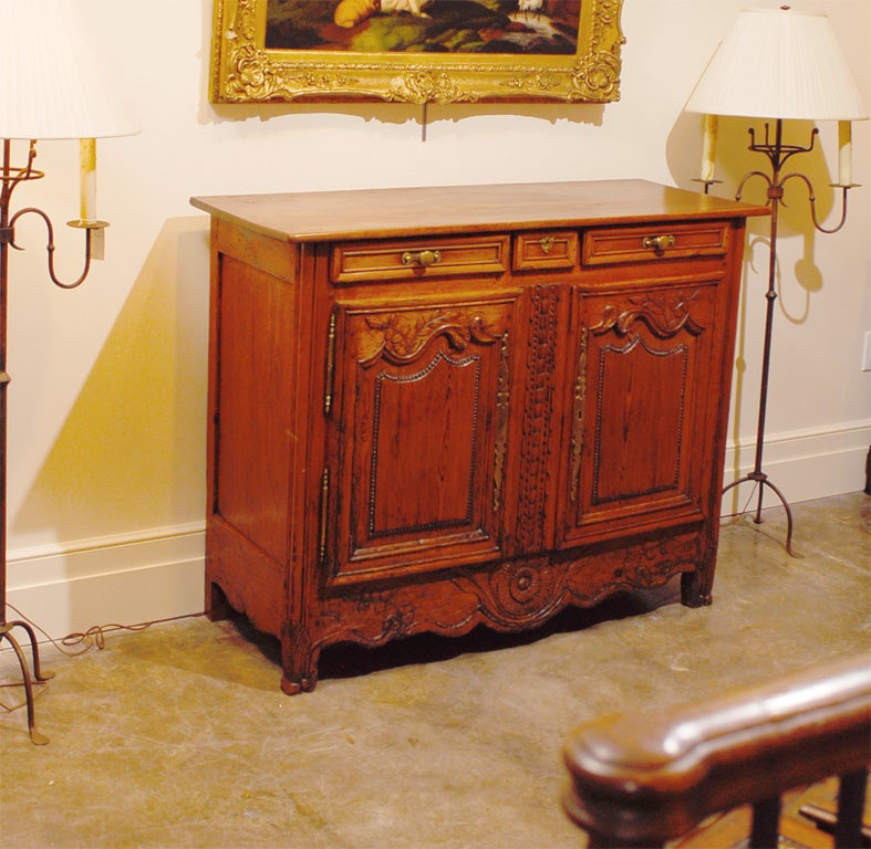 This French Provincial buffet from circa 1850 features a rectangular top over three drawers. Two doors open to reveal two shelves. These doors, made of curvilinear and recessed panels are adorned with exquisite foliage motifs and beading along the