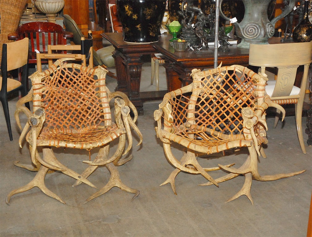 Antler armchairs with leather strappings, signed