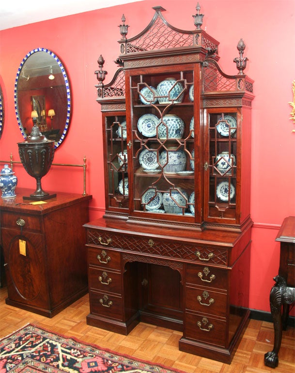 An 18th century mahogany Chinese Chippendale bookcase cabinet, circa 1780, the upper glazed breakfront section containing adjustable shelves and surrounded by intricate blind and open fretwork frieze, cornices and fanciful leaf and acorn finials,