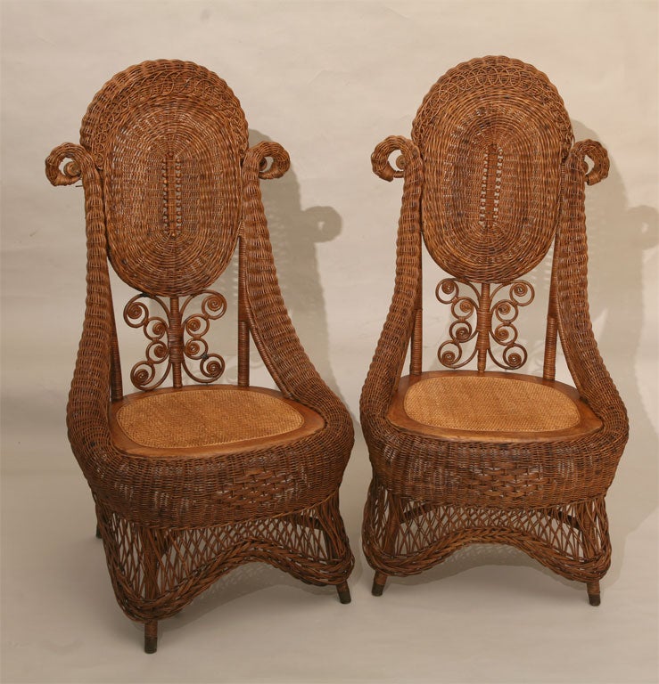 Rare matching pair of high style Victorian wicker side chairs in natural stained finish.  Graceful serpentine roll ending in rams horn design.  Cameo shaped upper back panels with wooden beading in center and reeded looping along rolled crest. 