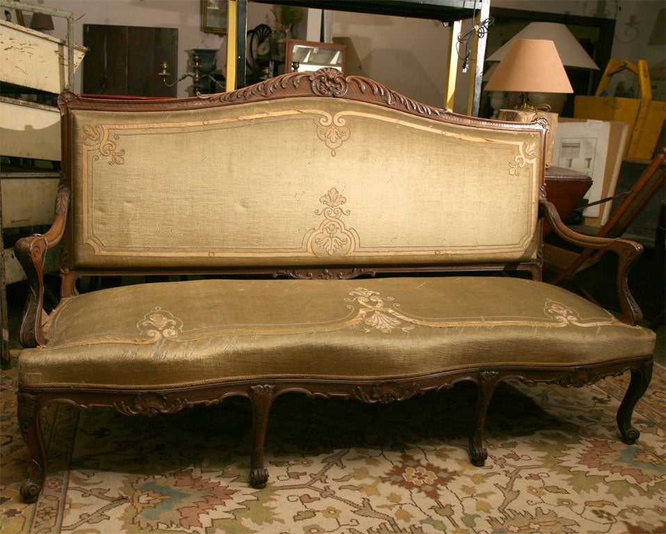 19th C., possibly earlier.  Gentle serpentine front with shell carving and delicate cross hatch details.  Although somewhat worn, the upholstery is in it's original velvet, hand appliqued and embroidered.