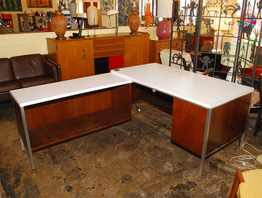 Strong L-shaped walnut desk with white formica top and chrome accents on the outer edges. Open storage on left hand side and two easy-glide drawers on right hand side.