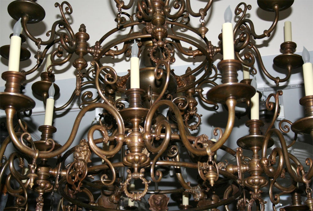 A 32 light three-tiered patinated bronze Dutch baroque style chandelier with arms issuing from rings of graduated size and converted from gas to electric and retaining the original gas jet keys. • Circa 1870 • 44” Drop, 48” Diameter