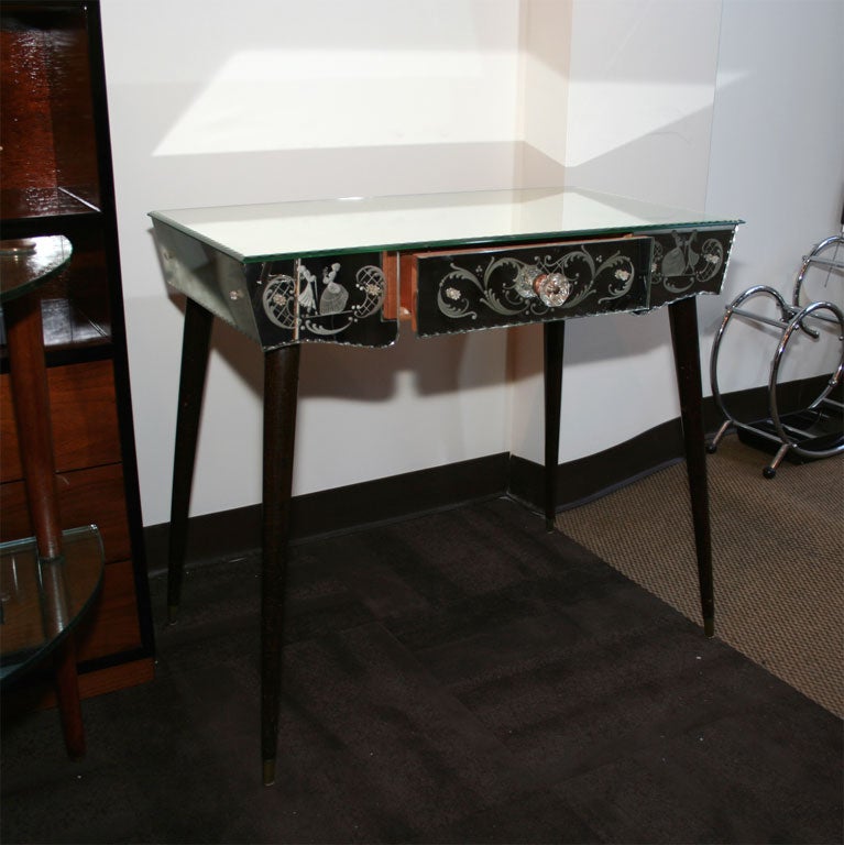 Mirrored vanity with reverse etched<br />
designs, chain beveled borders, and<br />
walnut legs.  Fitted with a center <br />
drawer with a cut crystal pull, and<br />
has rosette detailing throughout.