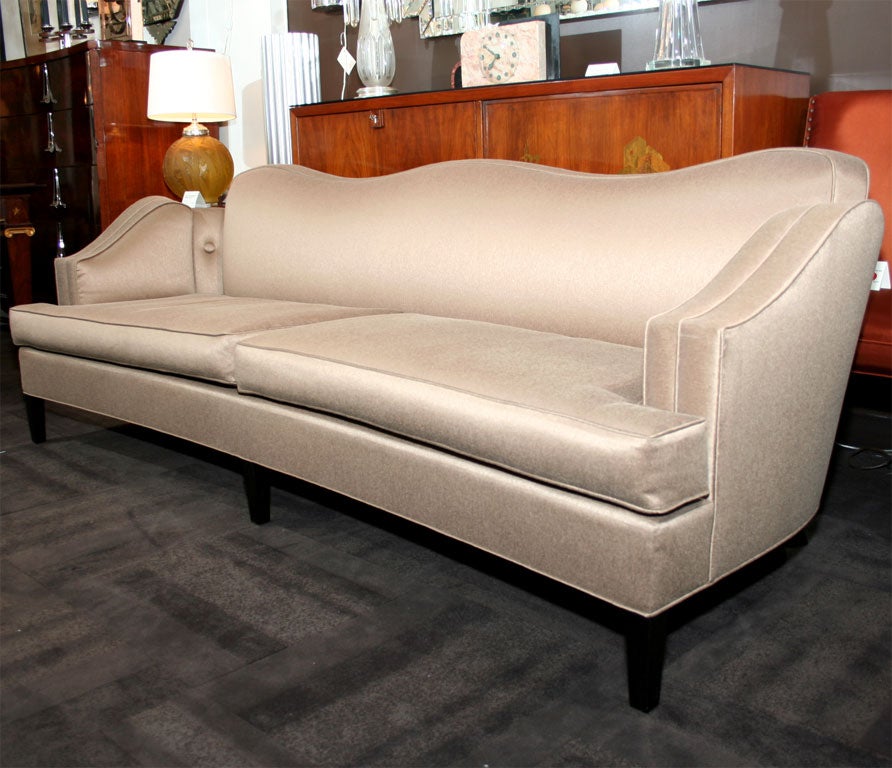 Stylized sofa with curved back design,<br />
and scrolled arms.  Sofa has ebonized<br />
mahogany legs and button detailing.